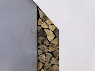 A close up of the wood neatly stacked in the cutout space next to the fireplace.