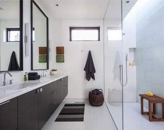 Metalword porcelain tile covers the floor of the bathroom. This space is made bright and airy thanks to the mostly white color scheme and skylight placed over the shower.