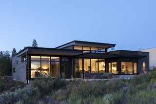Stained a warm charcoal gray, the cedar siding clads the exterior, while full-height glazing embraces views of the outdoors.