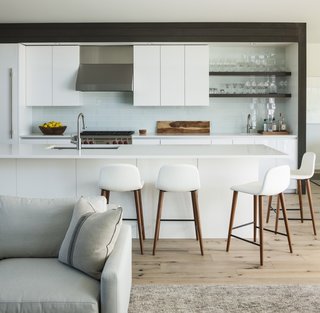 Designed to encourage communal cooking, the kitchen includes counter seating with Bacco Leather Counterstools (Design within Reach), as well as a built-in bar with a glassware display.