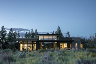 A view of the home seen from the southwest. The double-height living area, tucked behind the outdoor patio, occupies the heart of the home.