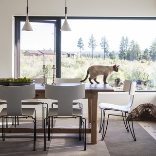 A vintage dining table built of reclaimed 18th-century English floorboards is combined with Donghia's Anziano chairs, which is a modern take on the ancient Greek Klismos chair.