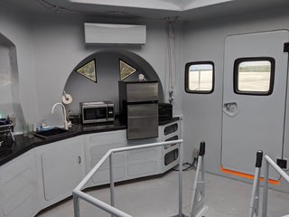 The door to the right of the galley kitchen opens to outdoor deck. A Fujitsu ductless heat pump is installed in the corner.