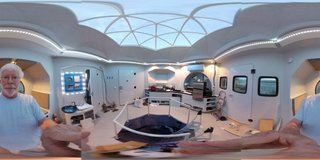 The geometric abode features an open core surrounded by external modules. The home has a galley kitchen, bathroom, breakfast nook, outdoor deck, and plenty of storage.