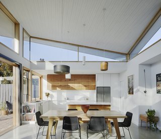 The new extension houses an open-plan kitchen, dining area, and living space. The hallway, flanked by bathrooms, leads to the original home that comprises three bedrooms and a lounge.