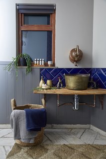An old brass jam pan has been repurposed into the bathroom sink, while the tap is a reclaimed French copper kettle.