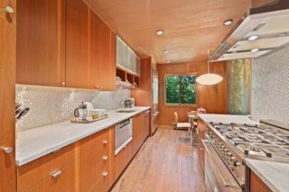 Accessed via the hall, the kitchen features mahogany cabinetry, a penny tile backsplash, and a breakfast nook. Appliances include a General Electric Monogram Refrigerator, a Bosch Dishwasher, a Dacor Microwave, and a Bertazzoni gas range with six burners and an oven.