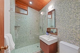 Located off the hallway, this bathroom features a glass-enclosed shower and high-end fixtures.