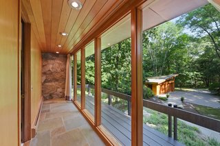 Located on the other side of the great room, the hall features a slate floor and full-height glazing. The light-filled passage provides access to the kitchen, "hotel" bedroom, bathroom, and den.