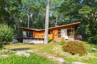 Built in 1956 by renowned local builder Vito Fosella, the two-story home embraces the wooded landscape with an exterior clad in teak, mahogany, and stone. The roof is tar and gravel.