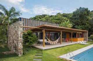 A pair of freestanding walls built of locally sourced natural stone bookend the pavilion-like living areas.