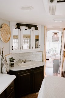 The cabinets were repainted and Giani countertop paint was applied to brighten up the corner sink and cabinetry. Stick-on subway tile from Tic Tact Tile was also applied as a backsplash.