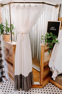 The creative duo tore out the glass shower and inserted a new surround built of wood (the same used in the entertainment center) and corrugated roof tin. The shower curtain is from Anthropologie.