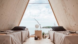 Overlooking stunning views of the archipelago, the one-bedroom building is furnished with two camping beds, a small cooking nook, and other locally procured sustainable furnishings.