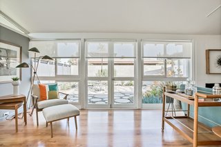 Walls of glass to the left of the entrance open up to an outdoor dining area. Hardwood floors are used throughout the open-plan great room.