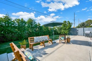 Accessible from the kitchen, this outdoor patio and lawn are shielded from the street corner by tall vegetation and a fence.