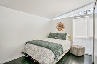The second bedroom with a full-height glazing overlooks the backyard pool.