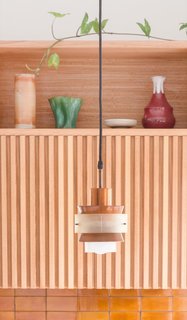 Refurbished vintage copper pendant lights hang above the kitchen’s handmade Manuka honey-colored tiles.
