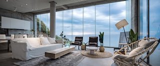 Faced with a giant wall of glass, the new concrete extension houses an open-plan living area, dining room, and kitchen.