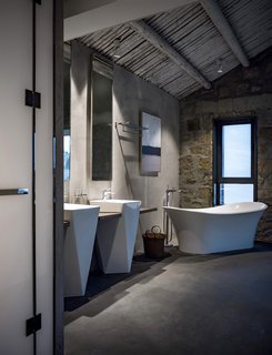 In contrast to the historic setting, the master bathroom is outfitted with modern fixtures including a double vanity, freestanding tub, shower, and toilet.