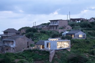 "The ‘new box’ on the site is made to be relatively inconspicuous," say the architects of the boxy, concrete extension. "In the presence of the time-honored beauty of 70-year-old houses and the supreme natural landscape, any fresh elements seem unnecessary and charmless."