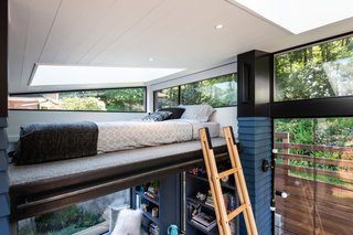 Accessed via collapsible ladder, the 58-square-foot loft bedroom with a queen mattress is located beneath an angled tongue-and-groove cedar ceiling that's painted white and punctuated by a large skylight. The floor is wool carpet.