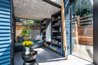 An abundance of shelving offers plenty of storage for the couple's books and knickknacks. The wallpapered ceiling, which hides cracks in the drywall and speakers, is Flashdance in Gray Matters.
