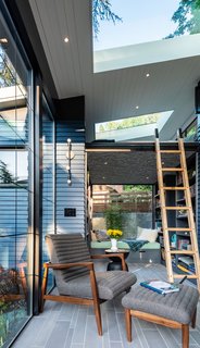 The gray-blue siding continues from the exterior to the interior to reinforce the seamless indoor-outdoor experience. The Callen chair and ottoman are from Room and Board.