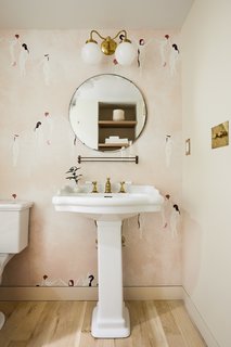 The Garden Bathroom serves as the powder room and the guest bathroom. The Maison C via Studio Four wallpaper complements the Benjamin Moore Bone White-painted walls.