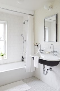 The kid's bathroom on the second floor is lined with white penny tile and white square tiles in a running bond pattern. The wallpaper is from Juju Papers.