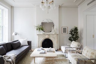 The living room gains an airy and modern update with new crown molding and walls painted Sherwin Williams Origami White. The clients also restored the living room's marble fireplace and painted the grate Benjamin Moore Black.
