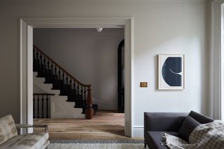 The large living room doorway was preserved and frames views of the original staircase that was restored with the treads, risers, and balustrades painted Benjamin Moore Black. The mahogany handrail was sanded down to its raw color and finished in a water-based clear coat.