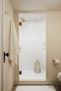 The shower is lined with matte white squares with an irregular, handmade feel. Matte white square penny tiles are used for the shower floor.