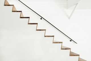 The elegant walnut steps are paired with a railing made of natural, hot-roll steel.