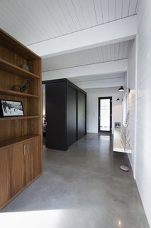 A compact bedroom is enclosed in the black volume just off of the entrance. A small bathroom lies adjacent.