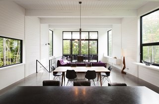 Polished concrete floors with integrated radiant heating are used throughout the home, while the walls are lined with white-painted wood planks.