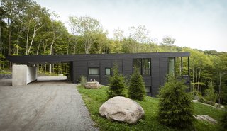 The home is clad in black-stained rough sawn cedar that has been sourced from Éco-Cèdre.