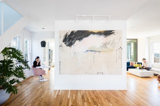 A massive art wall defines the entry space. The kitchen and an informal eating space are to the left of the art wall, while the dining and living areas (and connection to the backyard) are sited to the right.