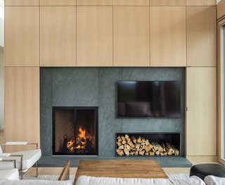 A custom wood-veneer paneled wall surrounds the wood-burning fireplace.