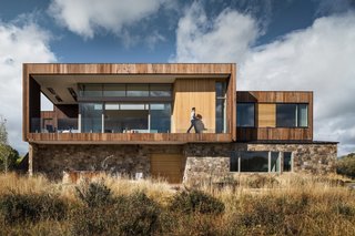 Rising out of the earth like a natural rock outcropping, the holiday retreat is clad in a combination of stained Western Red Cedar and stained Alaskan Yellow Cedar on the upper volume, while the lower is wrapped in stone veneer.