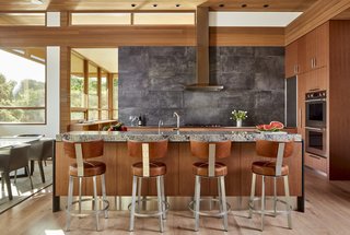 The kitchen is fitted with Dekton countertops by Cosentino, a porcelain tile backsplash by Iris Ecocrete, and custom wood-veneer cabinetry.