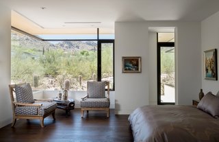 The master bedroom frames sweeping landscape views via a corner window.