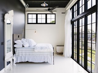The master bedroom opens up to the wraparound terrace. The Restoration Hardware bed is set against an accent wall that is painted Behr's Cracked Pepper.