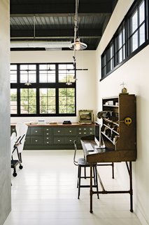 A vintage postoffice desk anchors one end of the office that's fitted with built-in cabinetry with a 16-foot-long walnut top on the far wall.