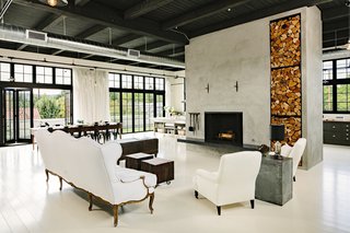 A massive concrete hearth, placed just off center, anchors the living room. The Douglas fir floors have been painted a creamy white.