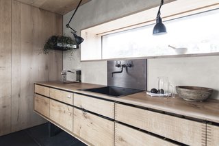 The kitchen has been custom-crafted from Danish oak, a material used throughout the home. A narrow ribbon-window provides panoramic views.