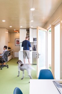 The meeting table is a Nelson X-Leg with birch wrap and a white-matte laminated top paired with Eames Molded Fiberglass in Peacock Blue. The kitchenette has been finished with Matte White Thermofoil cabinetry and a Caesarstone quartz countertop.