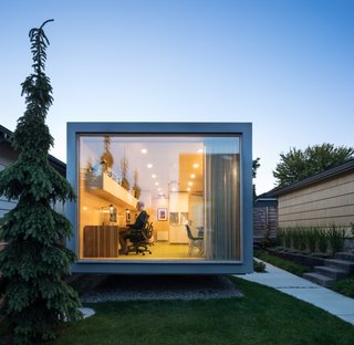 The floor-to-ceiling, triple-glazed wall overlooks the lawn and residence.
