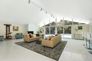 Lined with new terrazzo flooring edged with blue tile, the open-plan living room is anchored by a corner gas fireplace.