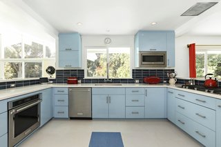 Walls were knocked down to create an open chef's kitchen, fitted with retro blue cabinetry and complemented by a dark blue tile backsplash.